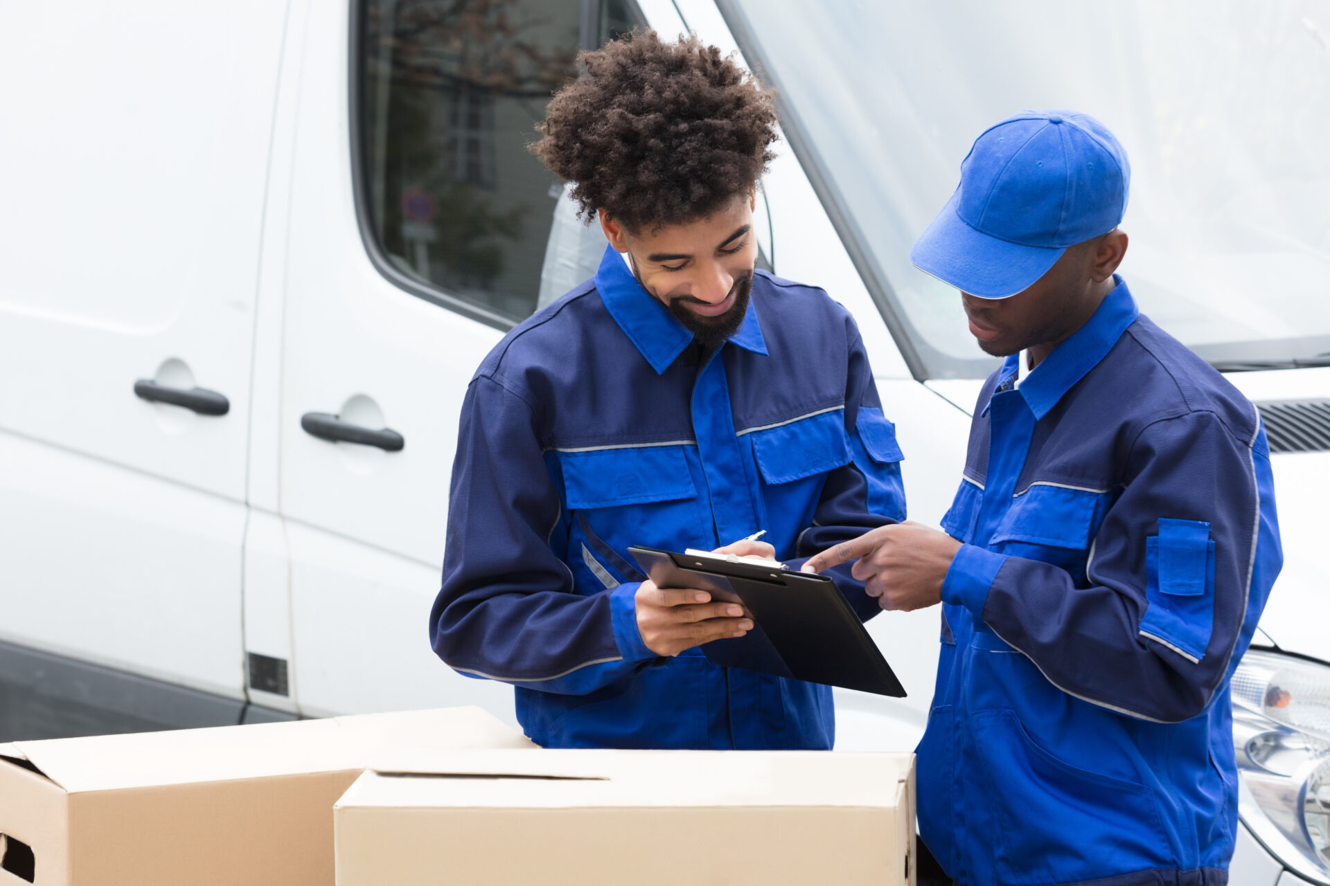 movers writing on a clipboard over moving boxes