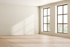 Light streaming through two large windows into an empty room.