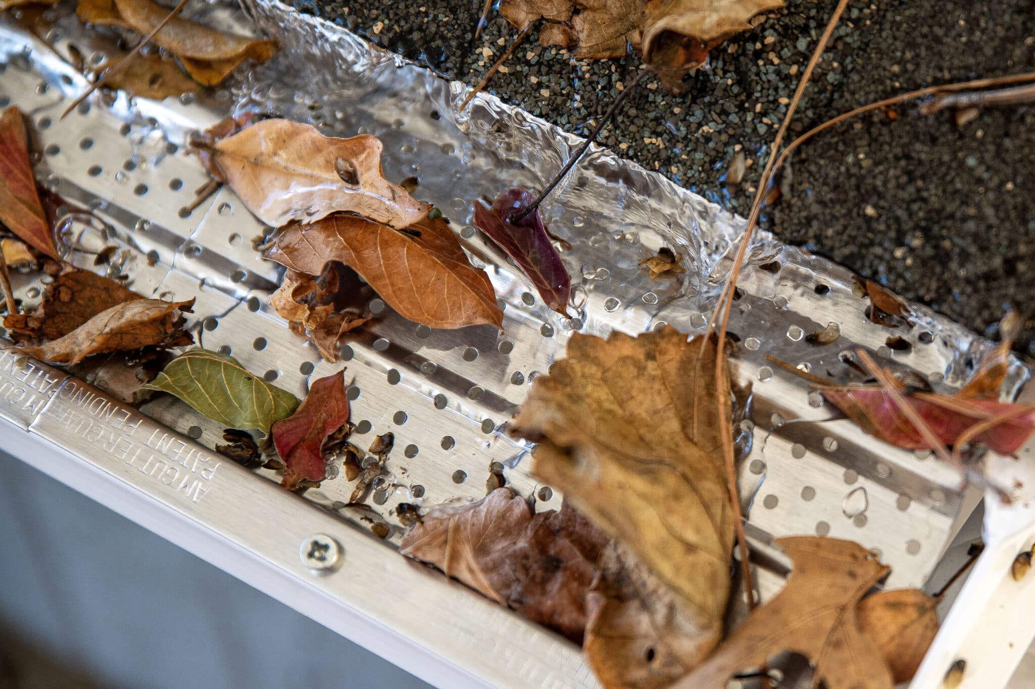 A-M gutter guard installed on roof line with leaves on top of gutter guard