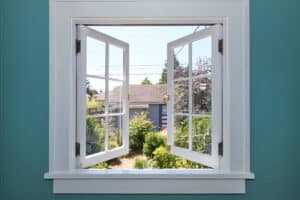 Open window to the back yard with blue wall.